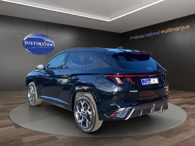 Vue 3/4 arrière droite du Hyundai Tucson noir 2026 avec spoiler de toit et jantes alliage distinctives.