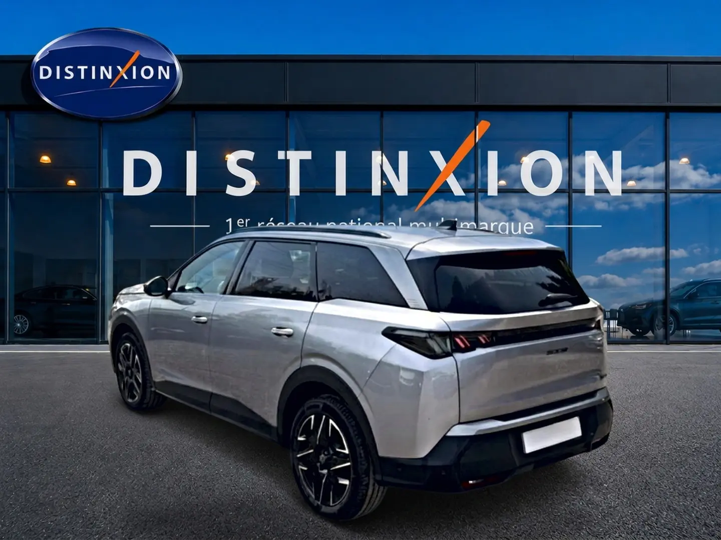 Peugeot 5008 Hybrid 145 gris artense en 3/4 arrière droit, avec vitres arrière surteintées et jantes alu noires.