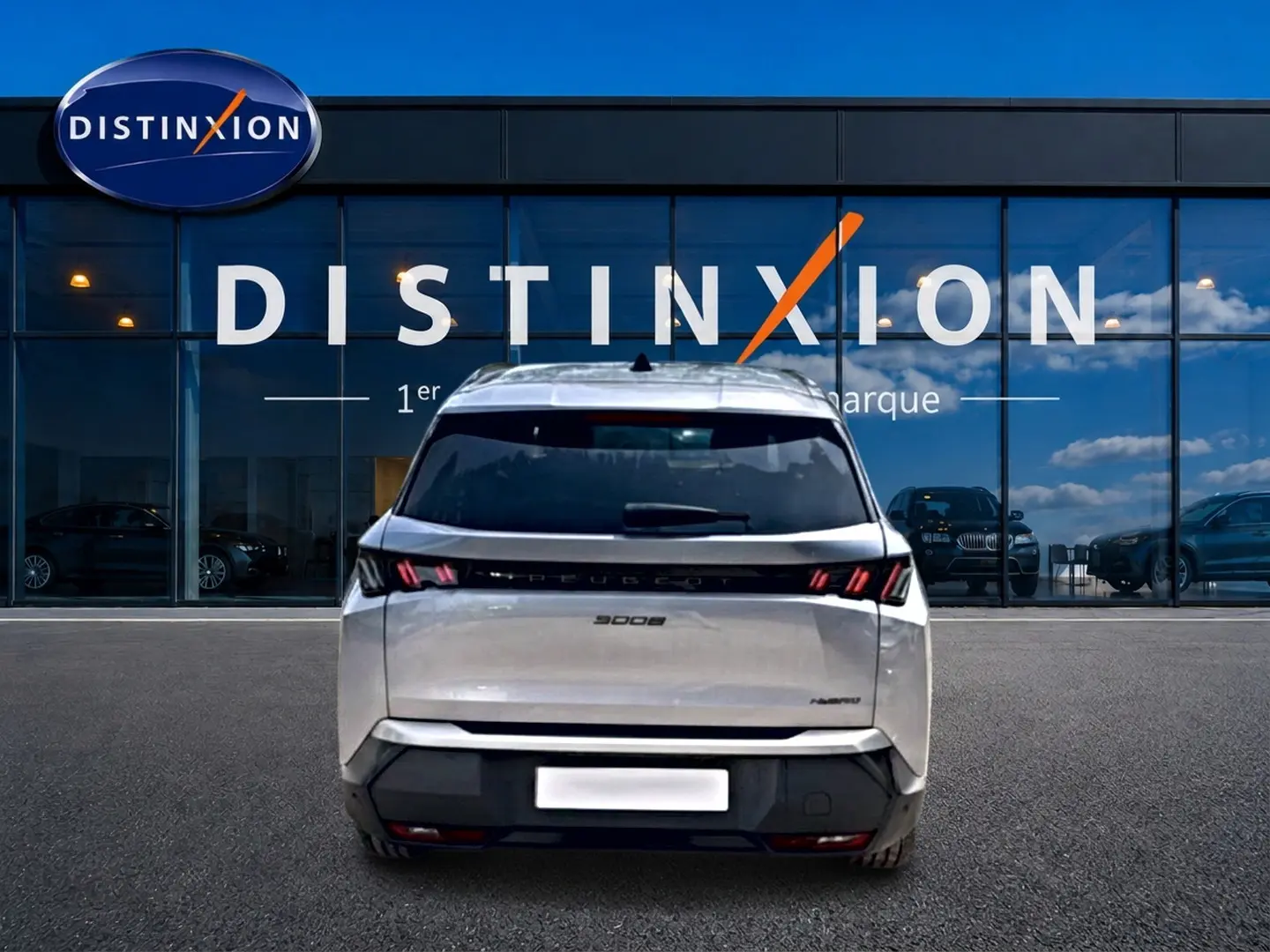 Vue arrière d'un Peugeot 5008 gris Artense avec feux LED caractéristiques, stationné devant une vitrine Distinxion.