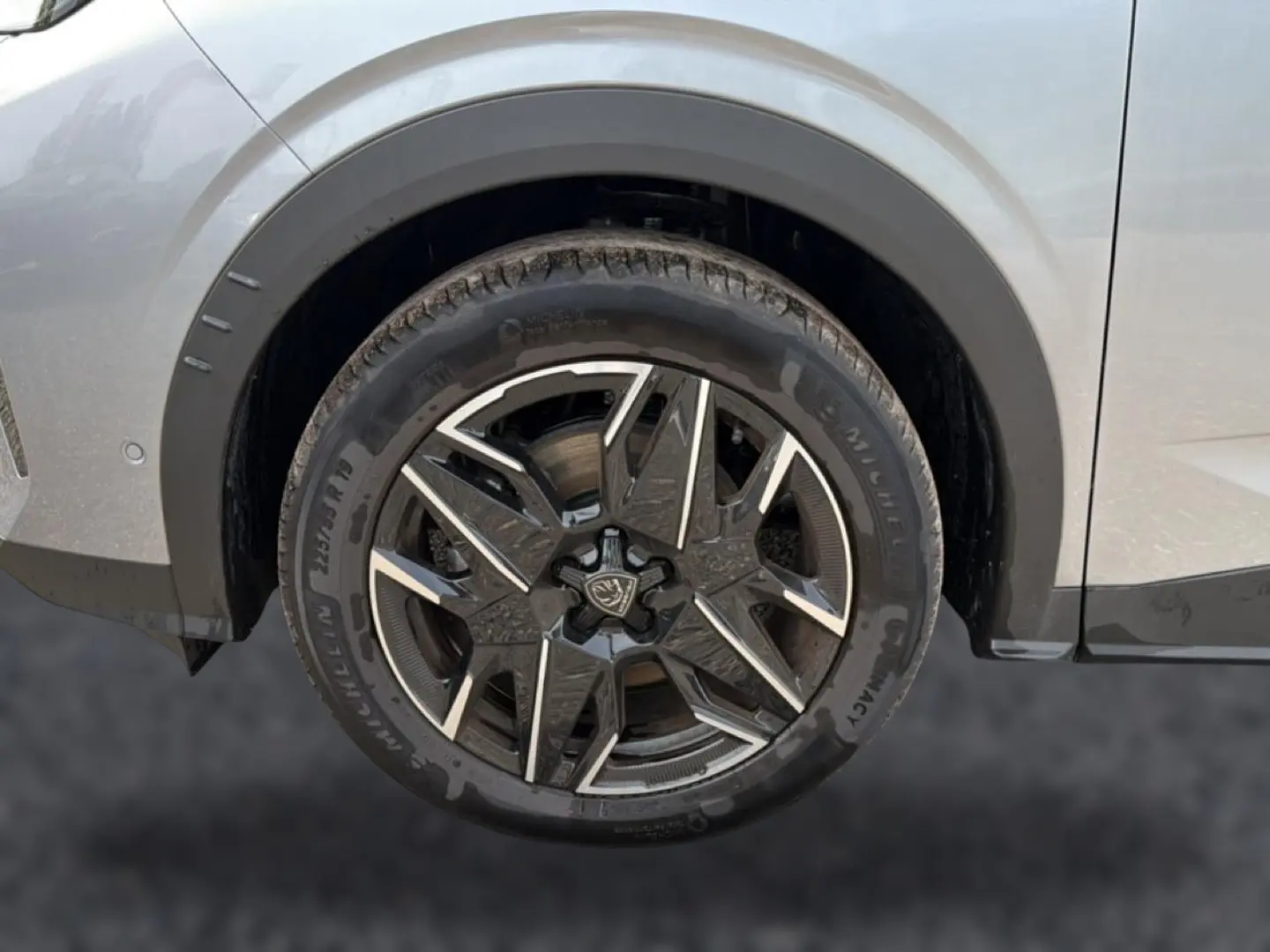 Gros plan sur la roue arrière droite d’un Peugeot 5008 gris Artense avec jante alu noire et argentée design moderne.