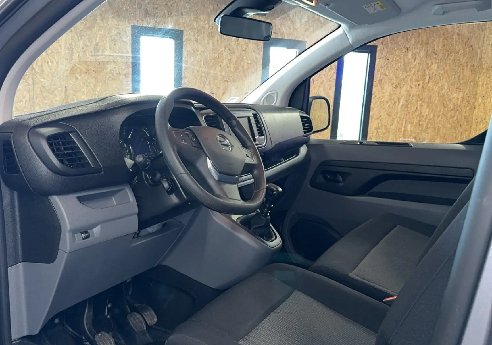 Intérieur de l'Opel Vivaro Combi 2022, vue côté conducteur, volant multifonction et sièges tissu gris visibles.