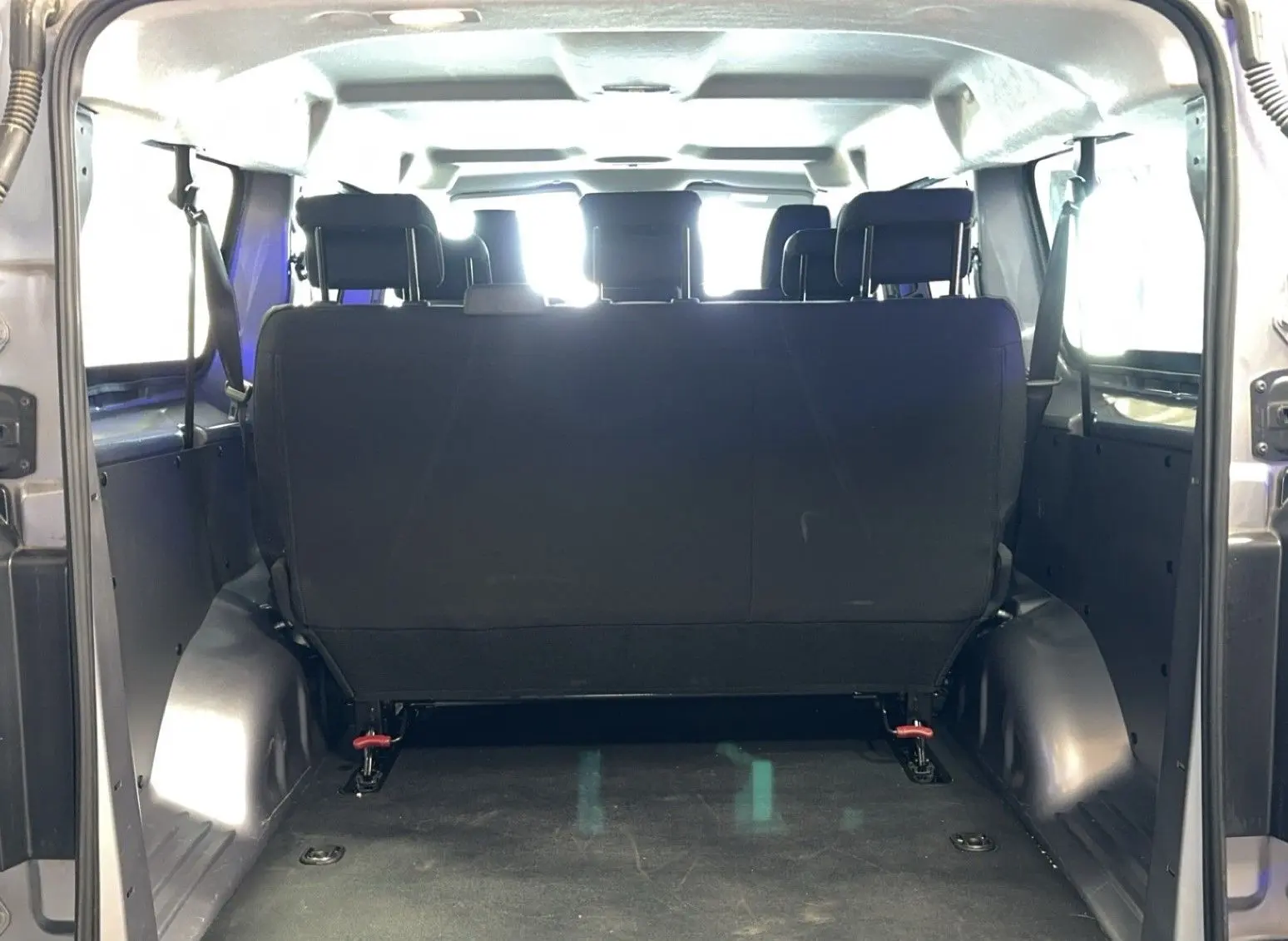 Vue arrière de l'habitacle d'un Opel Vivaro Combi gris 2022, montrant la banquette arrière en tissu noir.