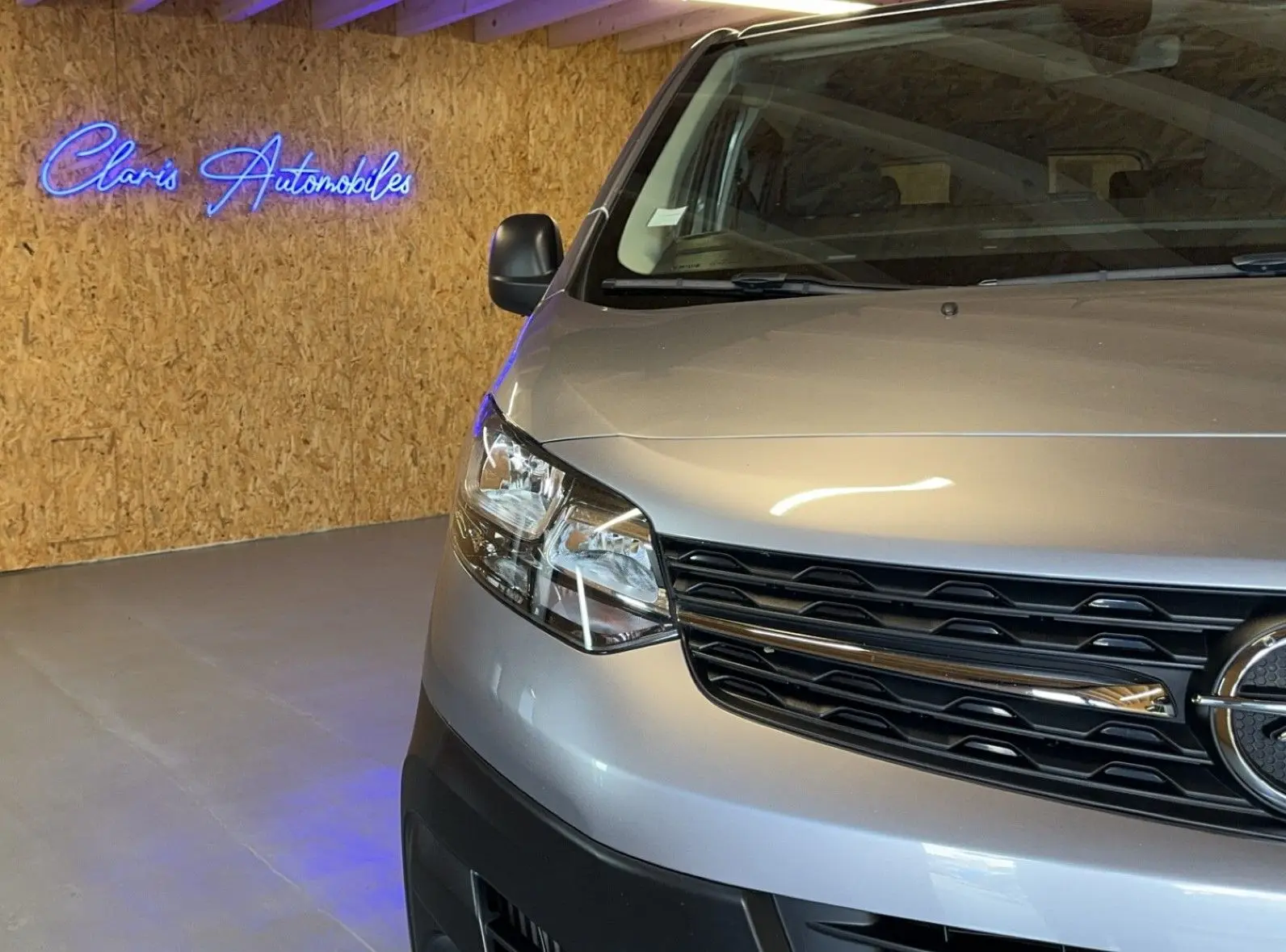 Vue de face partielle côté gauche d'un Opel Vivaro Combi gris 2022 avec calandre noire et phares modernes.