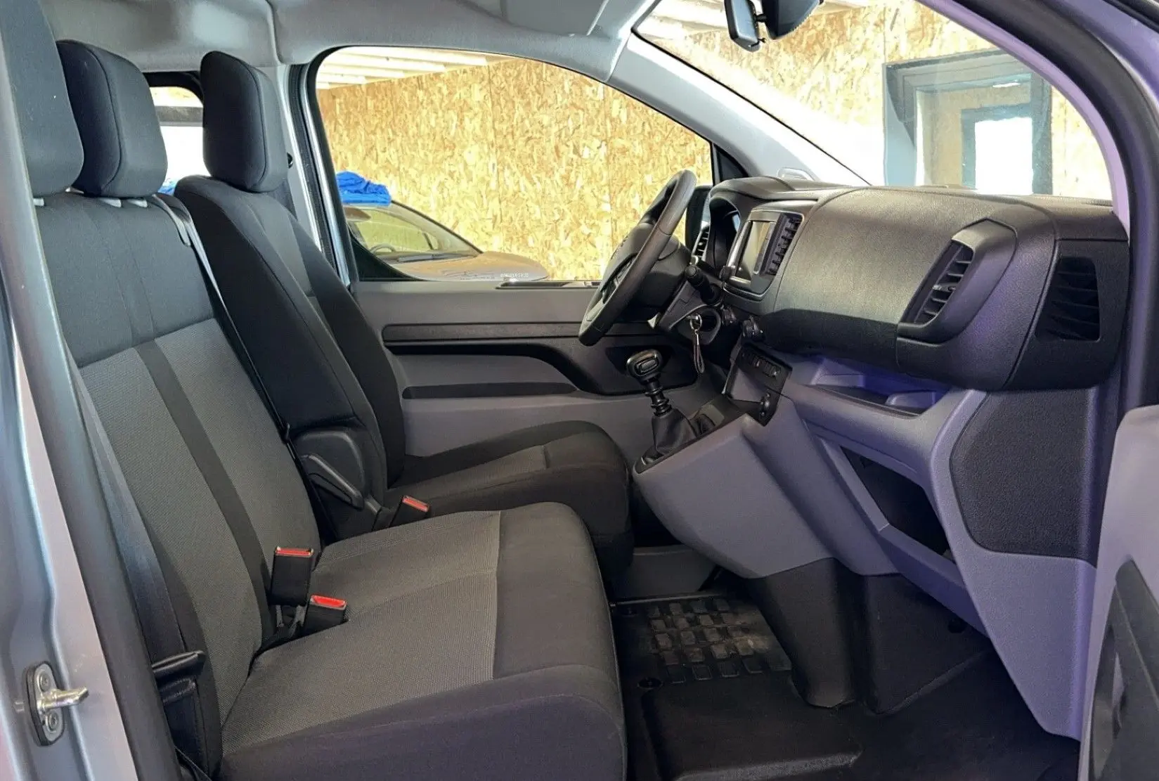 Intérieur côté gauche de l'Opel Vivaro Combi gris 2022, montrant les sièges tissu et le tableau de bord avec boîte manuelle.