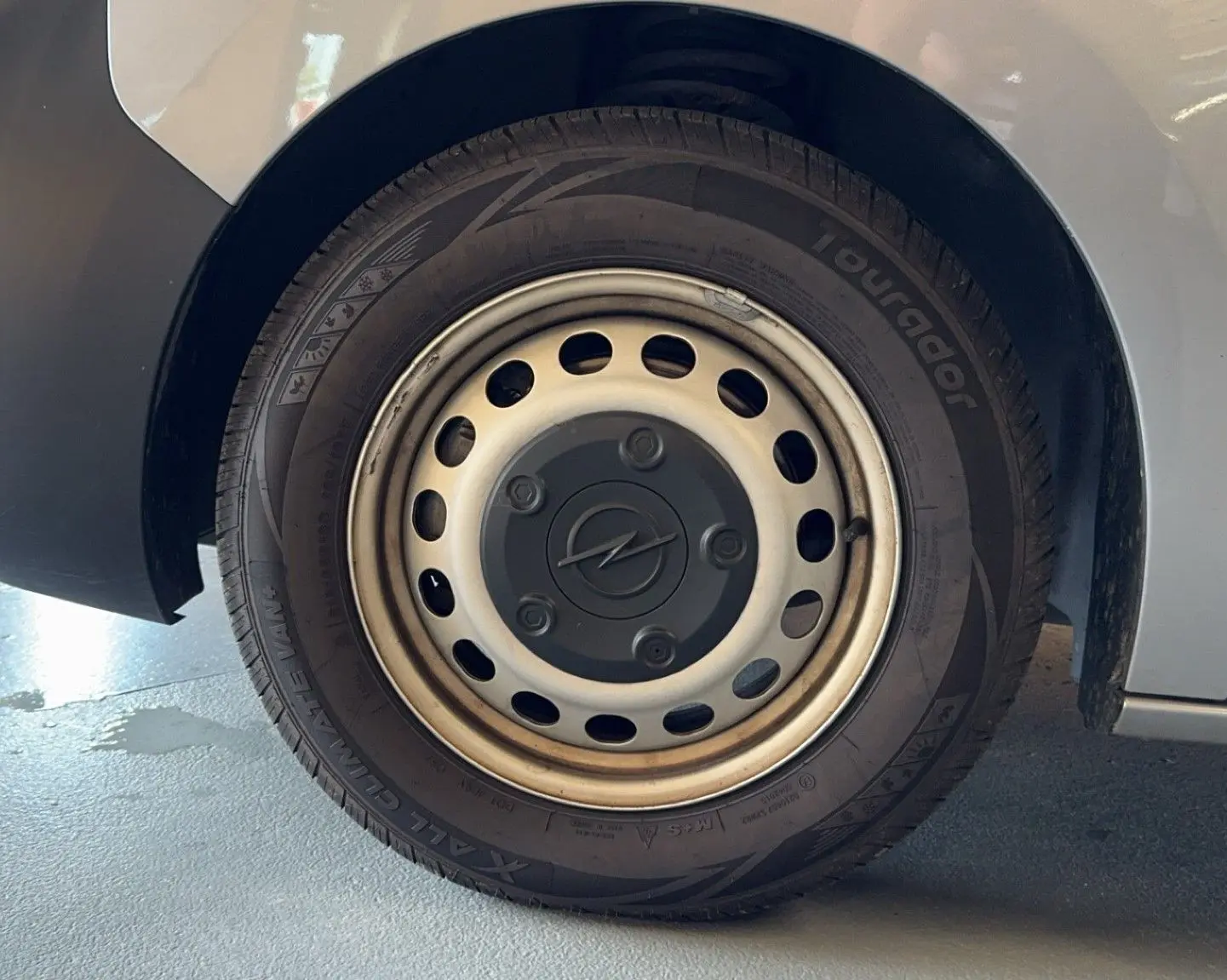 Gros plan sur la roue arrière droite grise d’un Opel Vivaro Combi 1.5 Diesel 120 avec jante acier et logo Opel central.