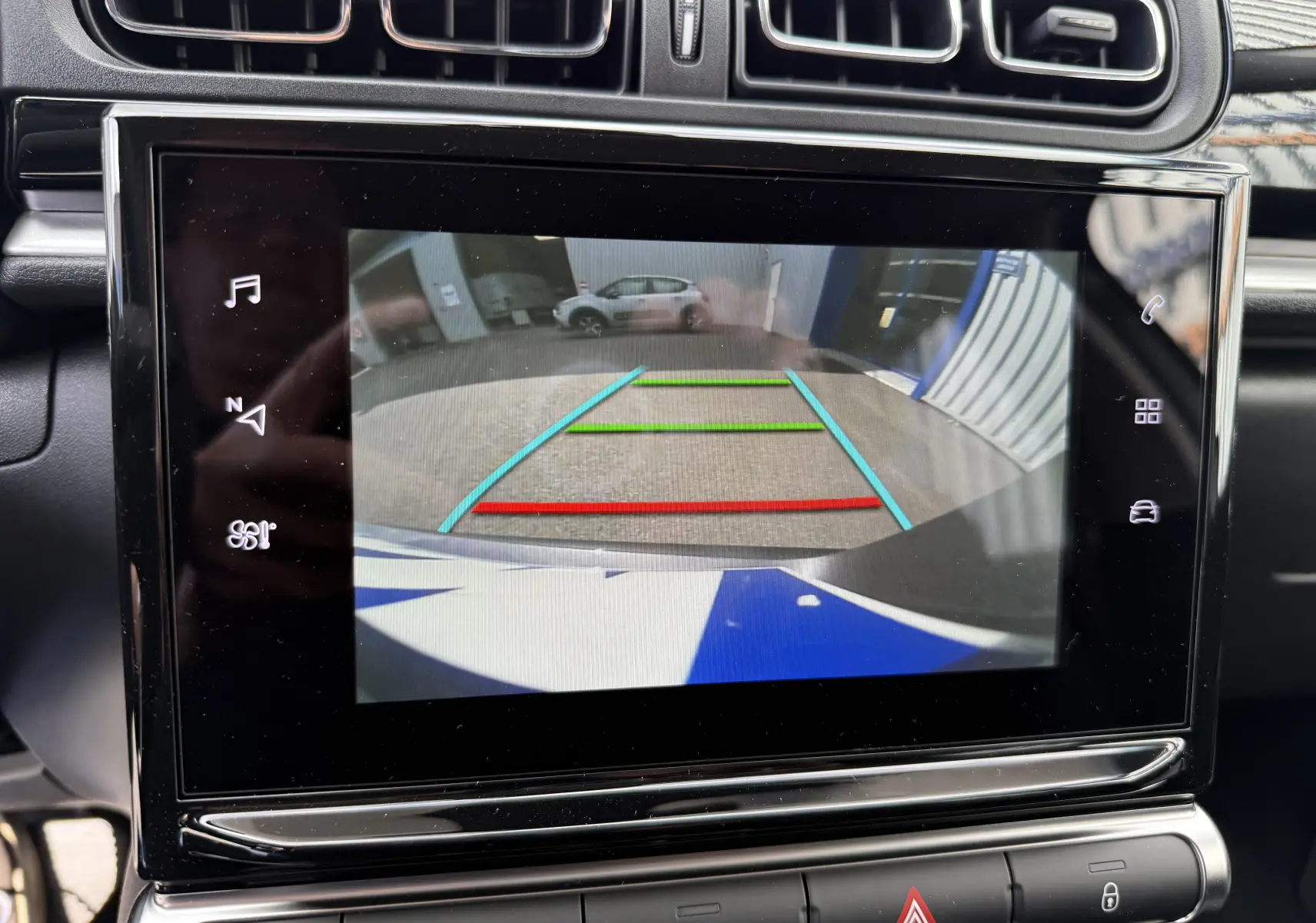 Écran tactile intérieur affichant la caméra de recul d'une Citroën C3 gris platinium avec lignes de guidage colorées.