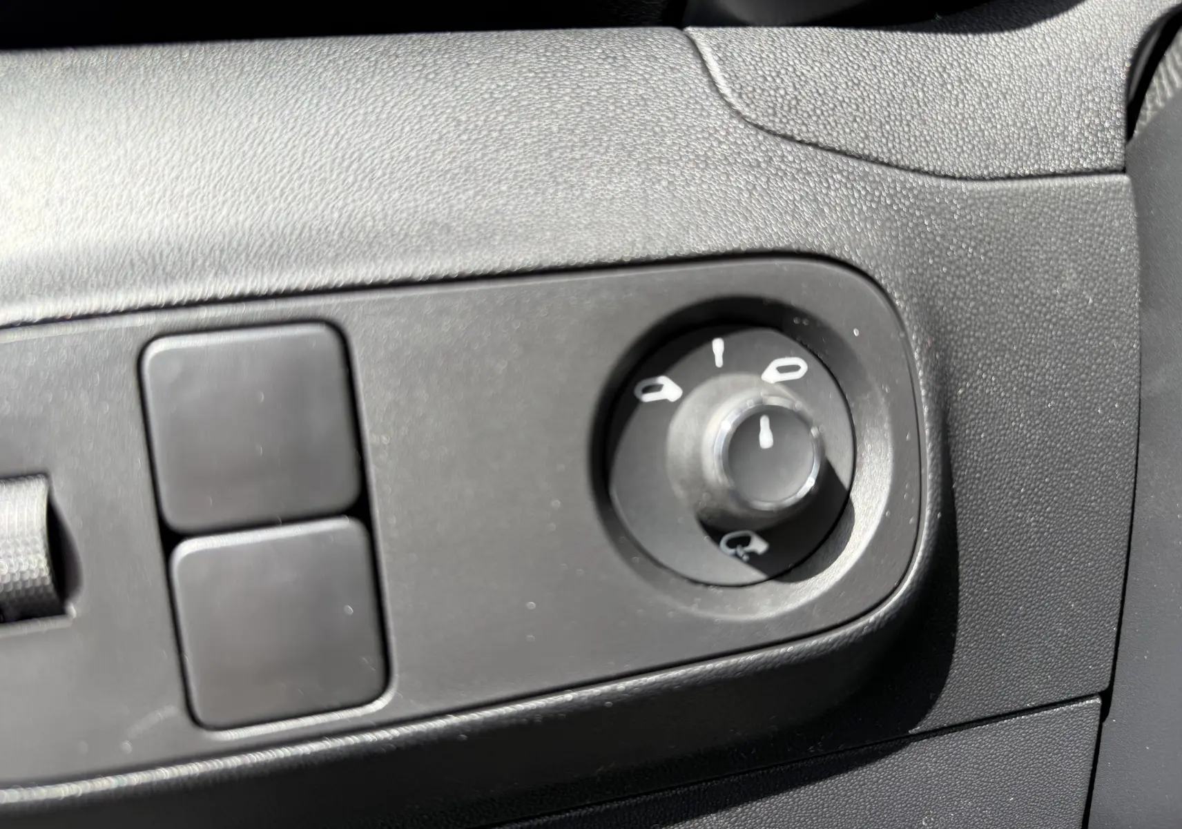 Gros plan sur le bouton de réglage des rétroviseurs dans l’habitacle noir d’une Citroën C3 gris platinium 2024.