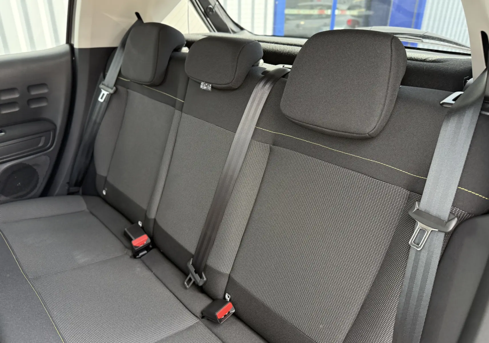 Vue intérieure arrière montrant la banquette noire et grise avec ceintures de sécurité de la Citroën C3 gris platinium 2024.