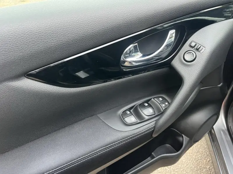 Détail de la porte avant gauche du Nissan Qashqai 2020 gris Squale avec commandes électriques et poignée chromée.
