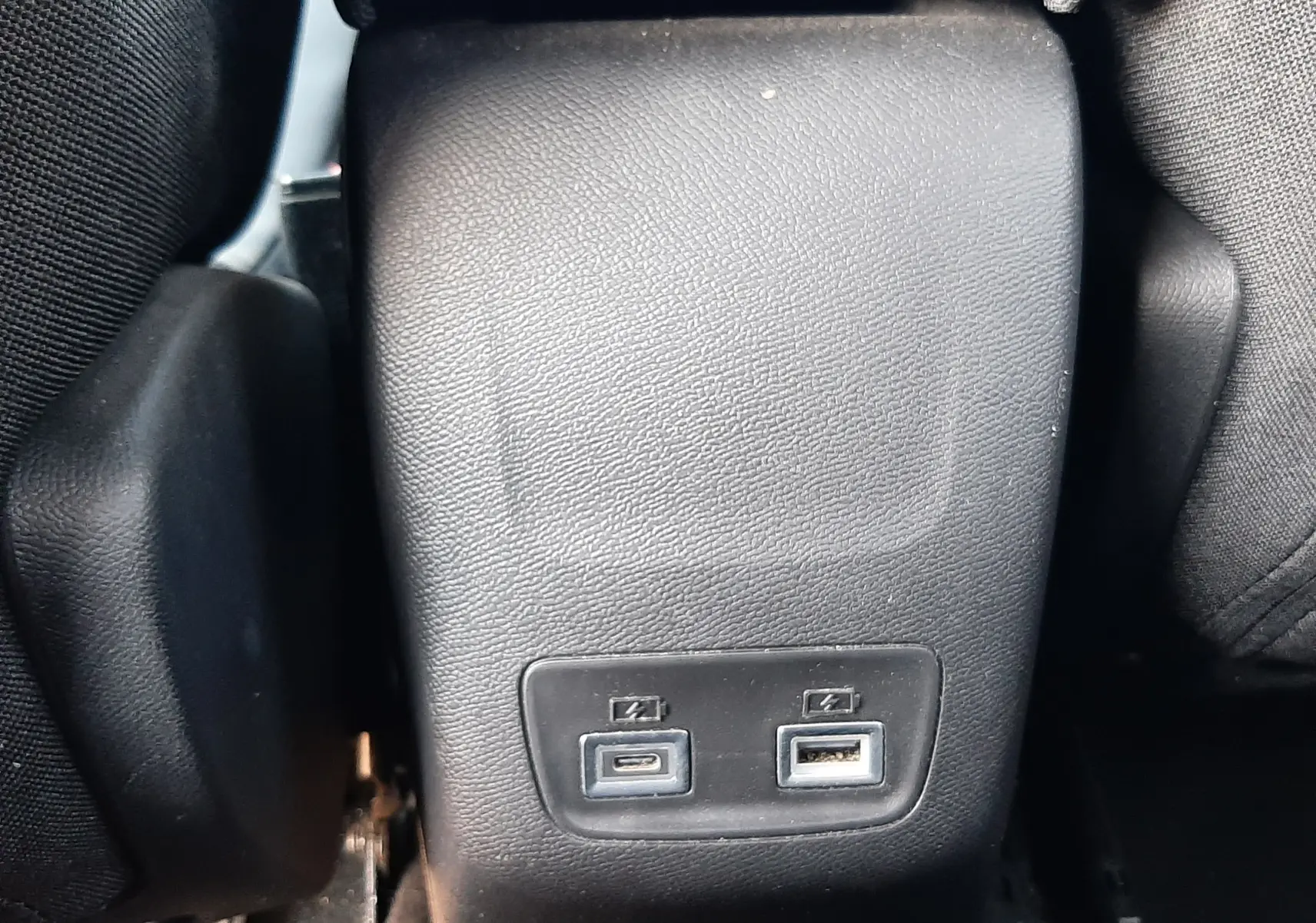Vue rapprochée de la console centrale arrière noire avec ports USB-C et USB-A dans un Peugeot 2008 Hybrid 145 Allure 2025.