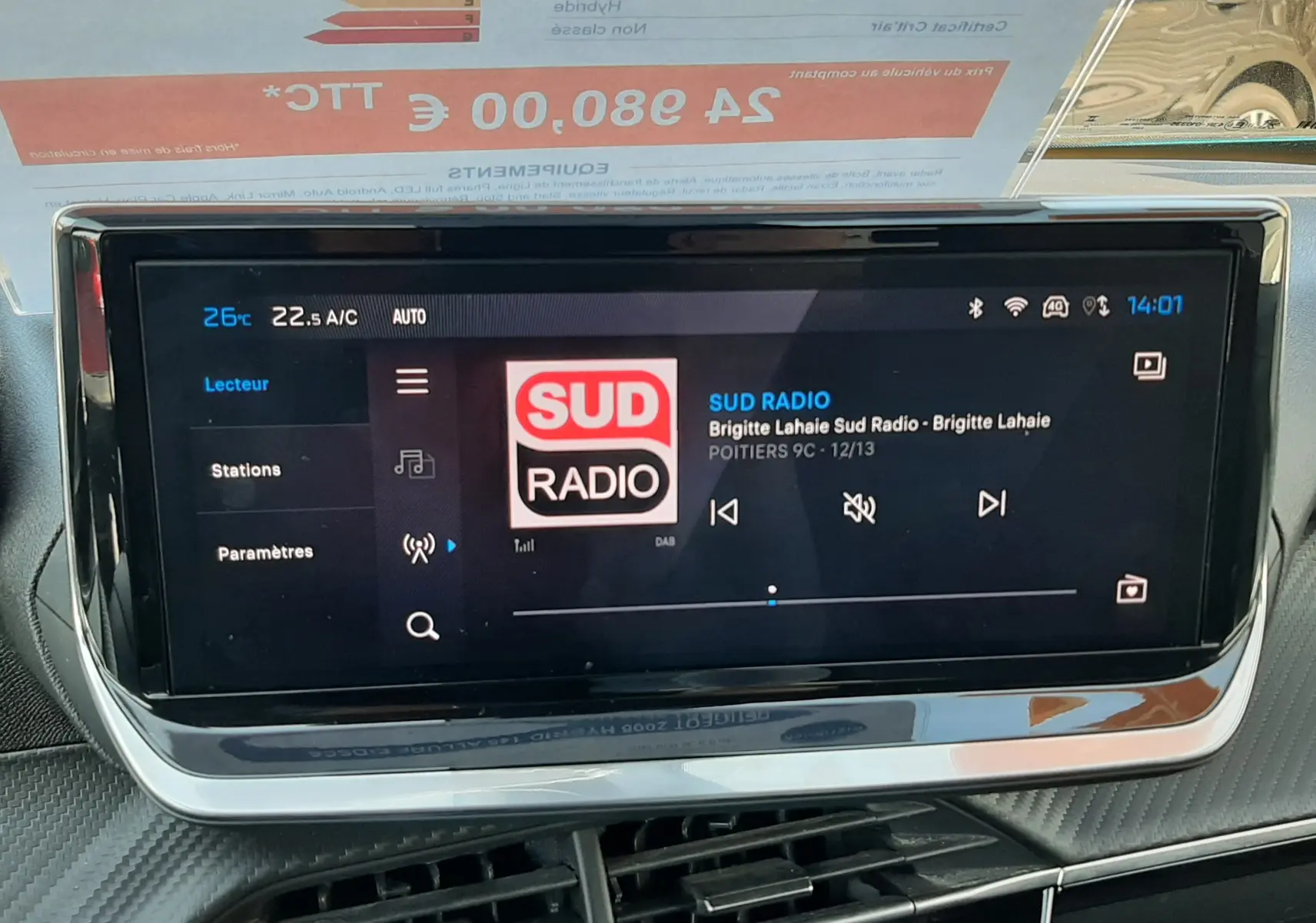 Écran tactile central du tableau de bord du Peugeot 2008 Hybrid 145 Allure en bleu Obsession, affichant la radio Sud Radio.