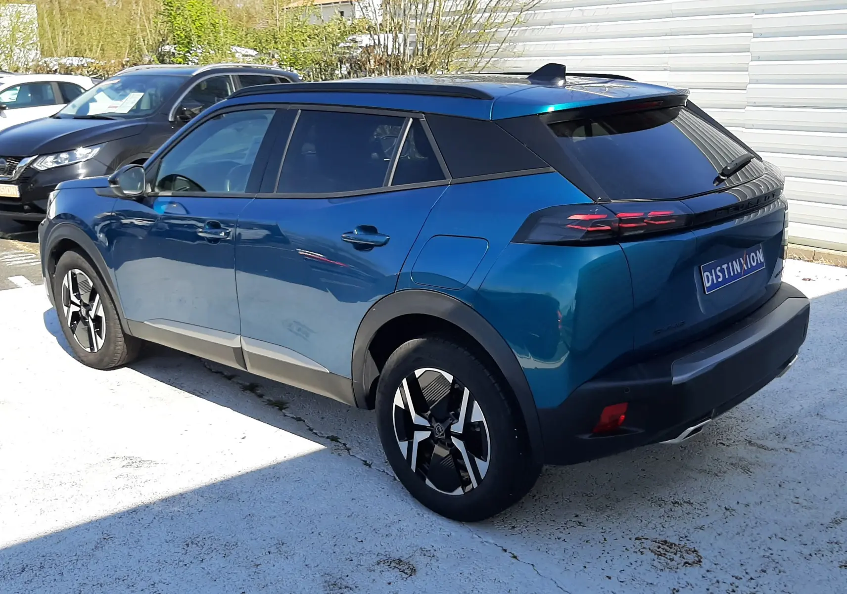 Peugeot 2008 Hybrid 145 Allure bleu obsession vue 3/4 arrière droit, toit noir et jantes bi-ton distinctives.