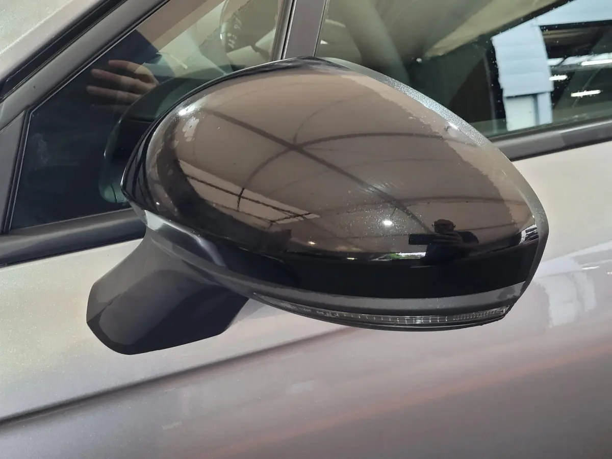 Rétroviseur extérieur droit noir brillant avec clignotant intégré sur Renault Clio gris foncé, vue rapprochée.