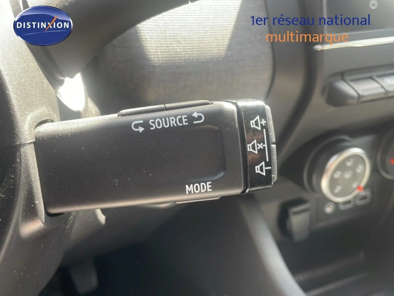 Gros plan sur la commande au volant de la Renault Clio blanche 2025, montrant les boutons source et mode.