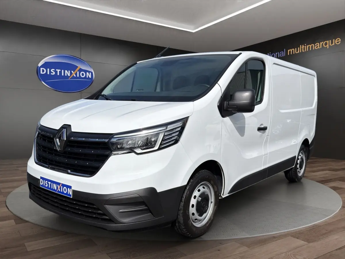 Fourgon Renault Trafic blanc en vue 3/4 avant droit, avec calandre noire et phares LED distinctifs.