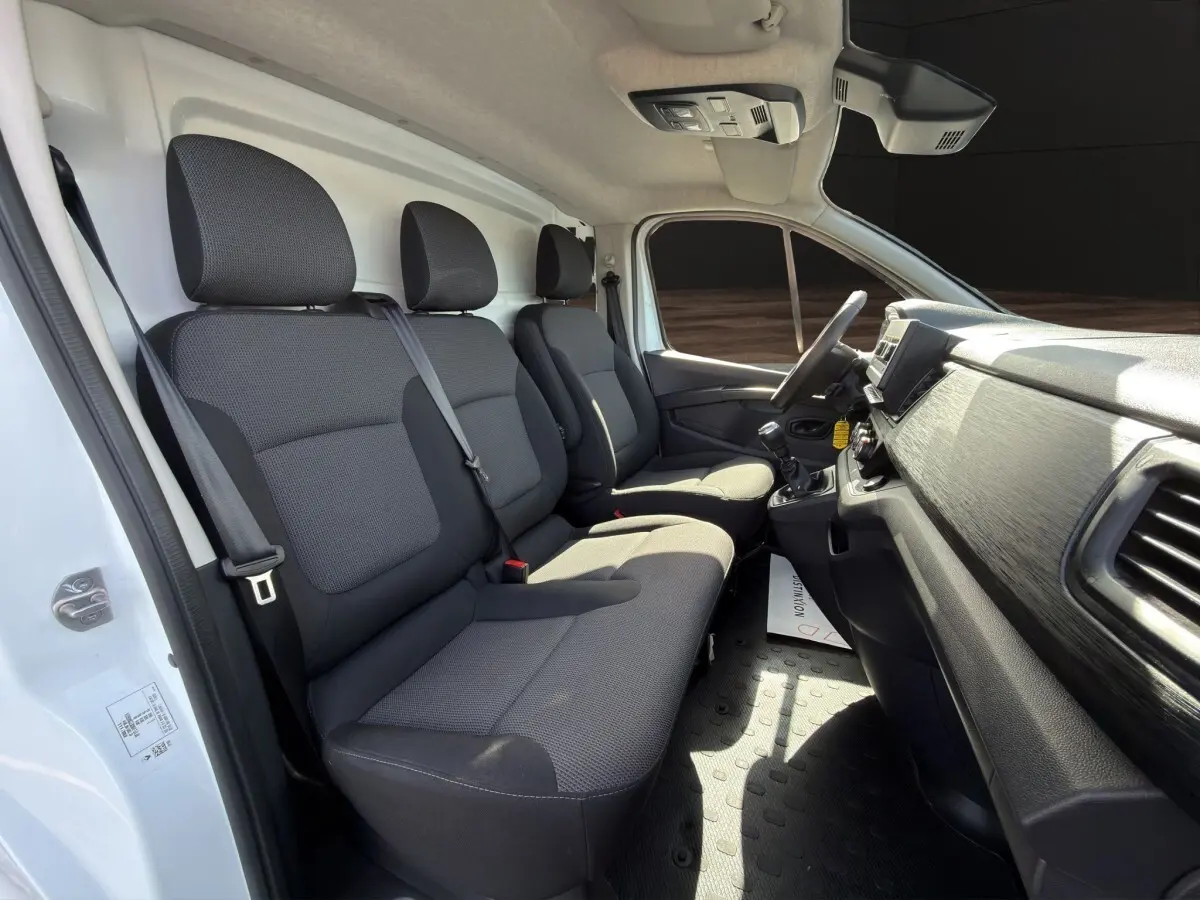 Vue intérieure côté conducteur du Renault Trafic Fourgon blanc 2024, montrant les sièges avant et le tableau de bord.