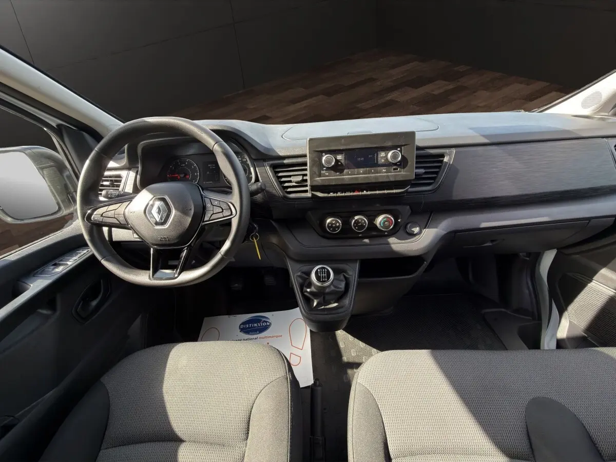 Vue intérieure avant du Renault Trafic Fourgon blanc 2024, montrant le volant multifonctions et la console centrale avec écran.