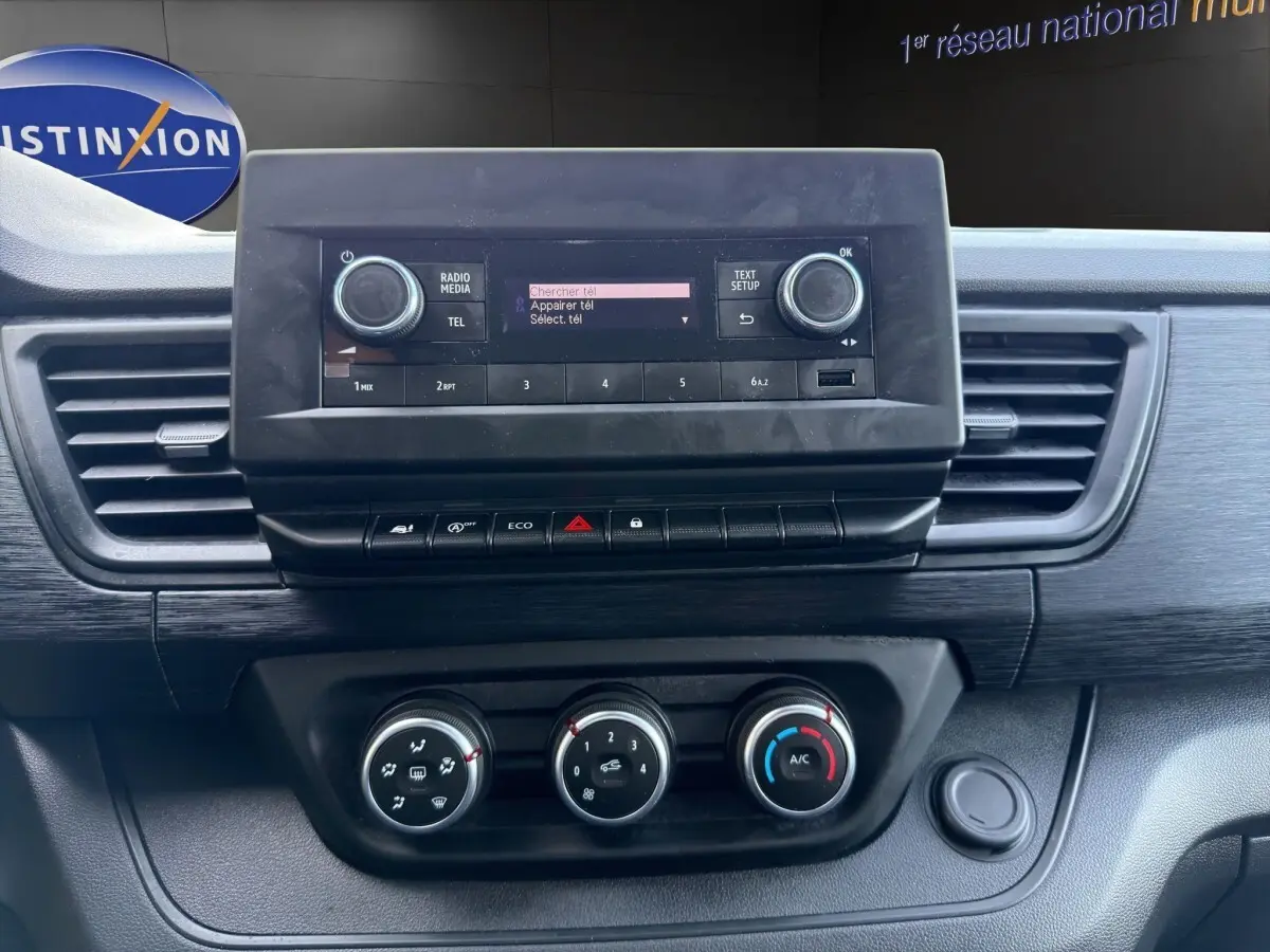 Vue rapprochée du tableau de bord noir du Renault Trafic Fourgon 2024 avec écran central et commandes de climatisation.