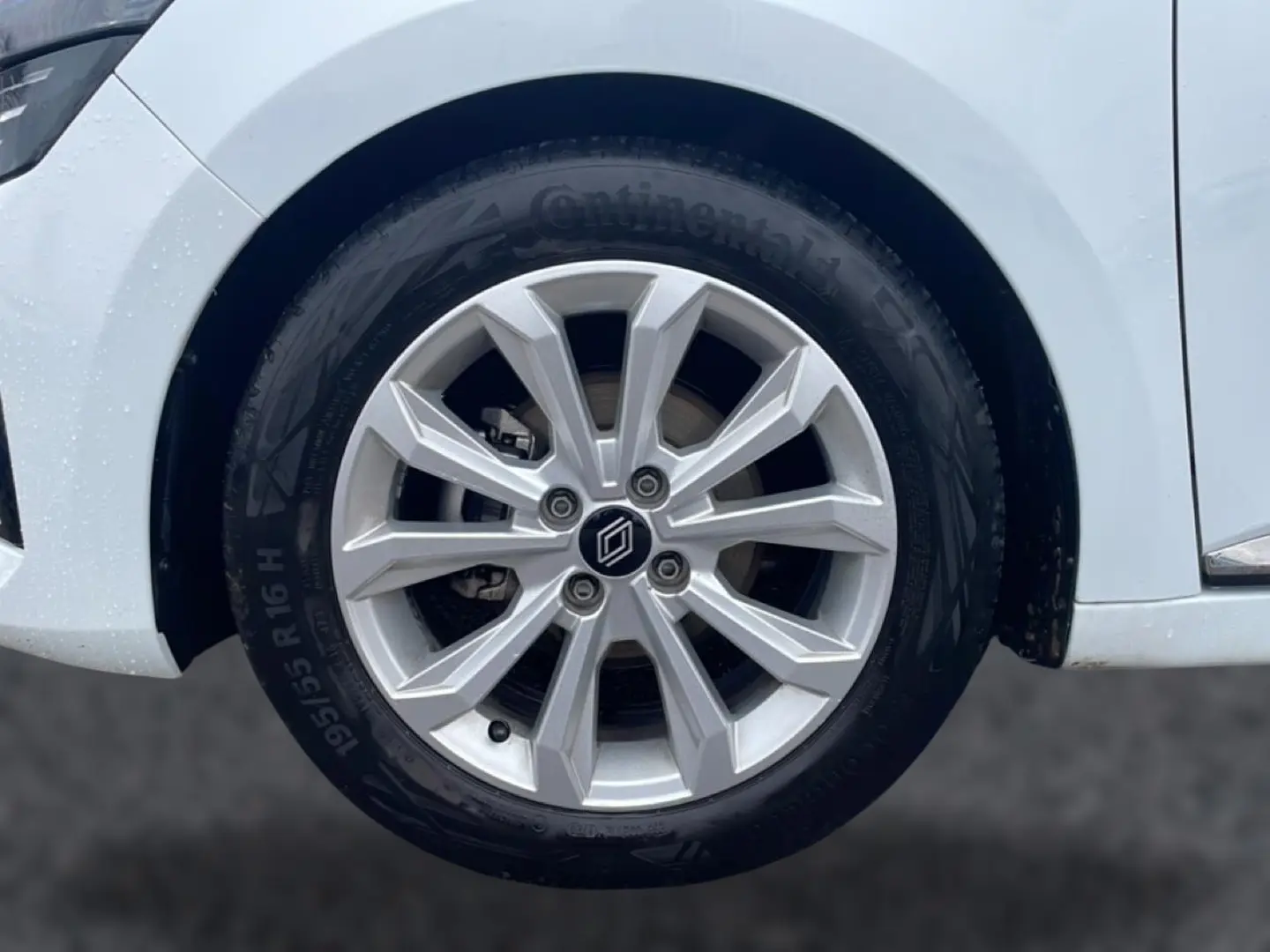 Gros plan sur la roue avant gauche de la Renault Clio V blanche, avec jante alliage 16 pouces et logo central.