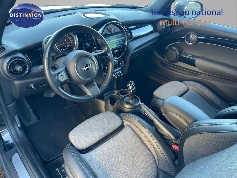 Vue intérieure côté conducteur du MINI Cabriolet Cooper 2023 en Midnight Black II, volant cuir et sièges tissu noir-gris.