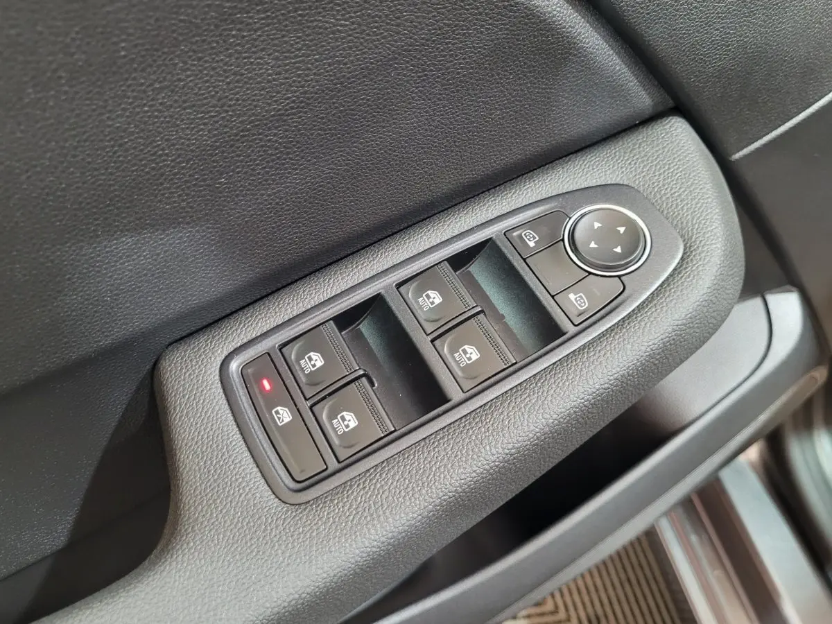 Gros plan sur les commandes de lève-vitres et rétroviseurs côté conducteur d'une Renault Clio gris foncé 2025.