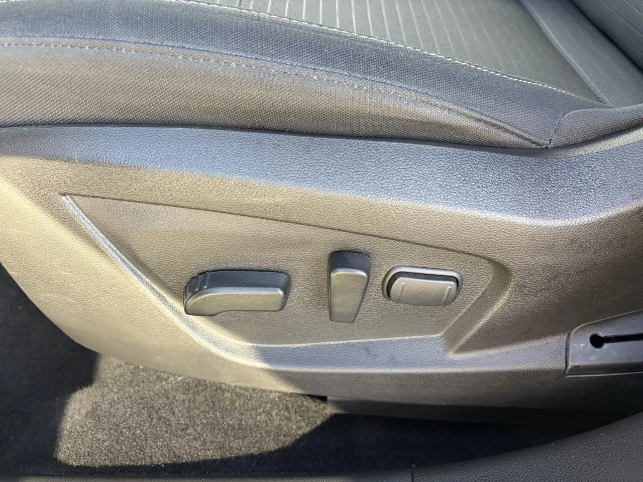 Détail des commandes de réglage électrique du siège conducteur sur Renault Arkana blanc Glacier, intérieur noir.