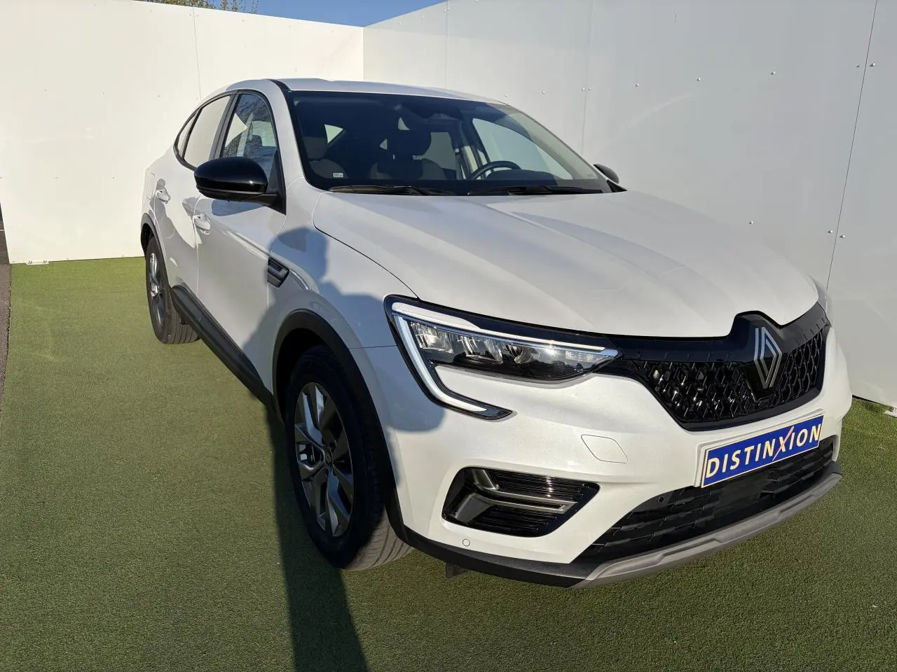 Renault Arkana blanc glacier en 3/4 avant droit, avec calandre noire et jantes alliage grises 17 pouces.