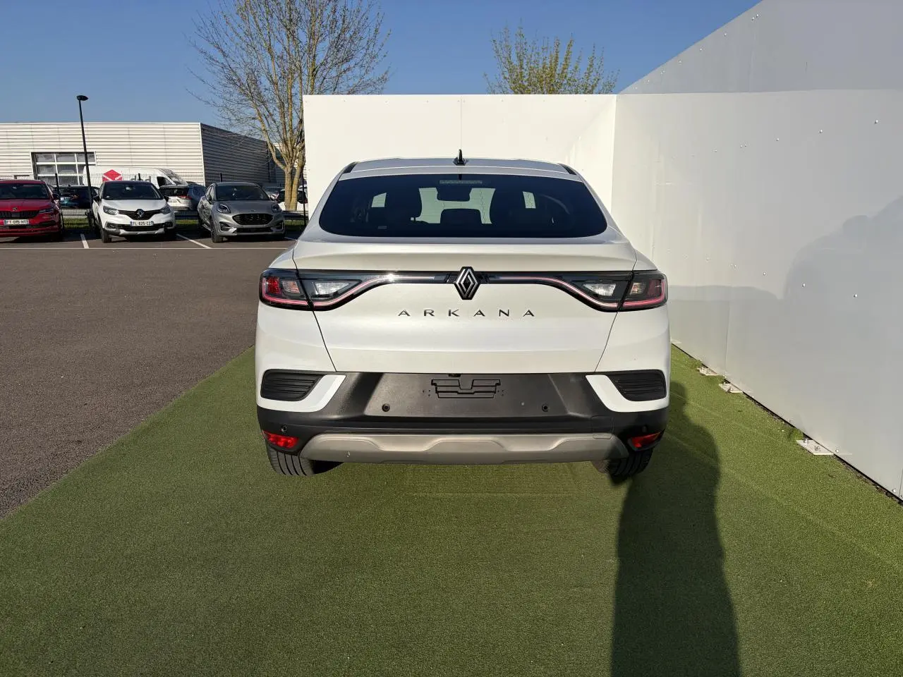 Vue arrière d'un Renault Arkana blanc glacier 2025 avec feux LED reliés par un bandeau lumineux noir.