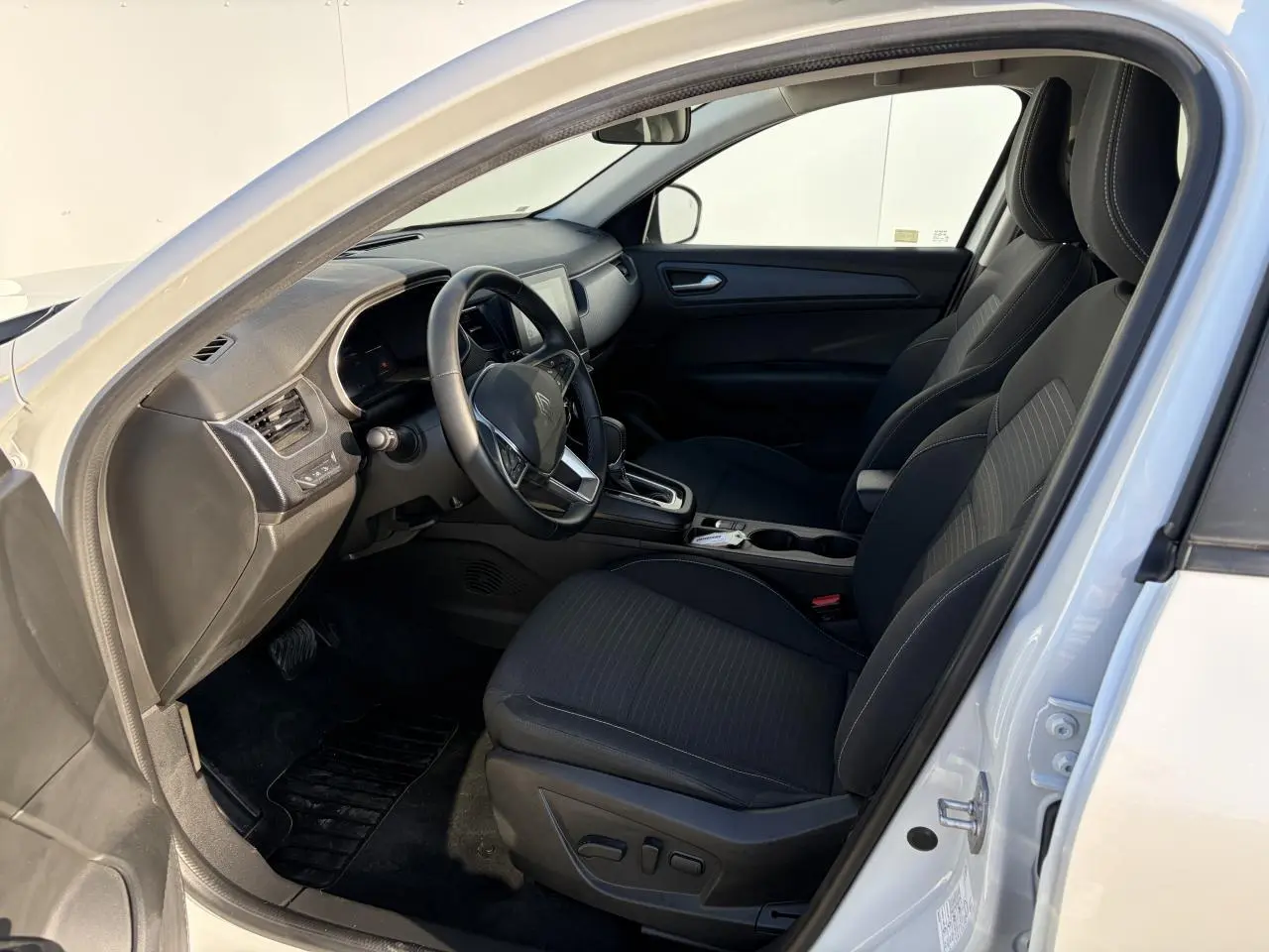 Vue intérieure côté conducteur d'un Renault Arkana blanc glacier 2025 avec sièges noirs et tableau de bord moderne.