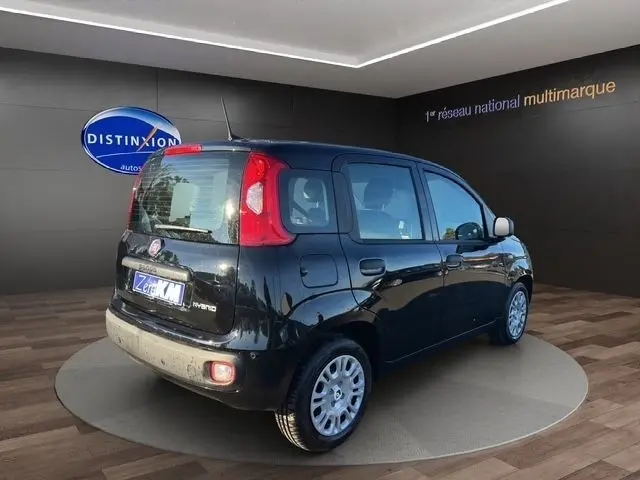 Vue 3/4 arrière droite d'une FIAT Panda noire 2025 avec feux arrière verticaux et jantes argentées en exposition showroom.