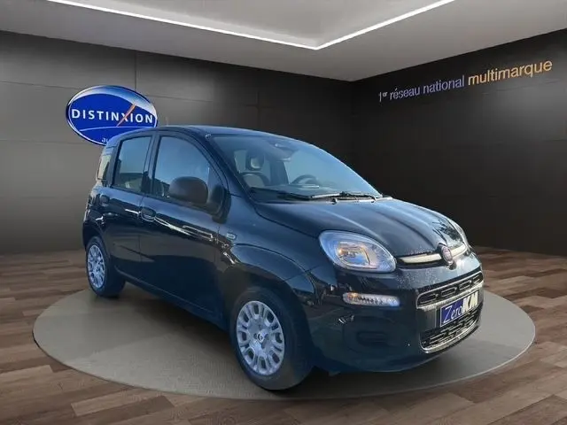 Vue 3/4 avant droite d'une FIAT Panda noire 2025 avec phares halogènes et jantes acier argentées dans un showroom.