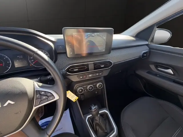 Vue intérieure côté conducteur de la Dacia Sandero Stepway gris foncé, avec écran tactile central et volant multifonctions.