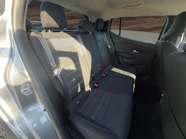 Vue intérieure côté gauche des sièges arrière noirs du Dacia Sandero Stepway gris foncé avec ceintures et appuie-têtes visibles.