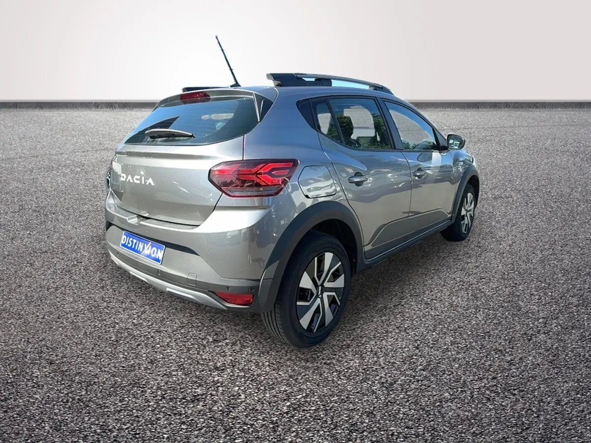 Vue 3/4 arrière droite d'une Dacia Sandero Stepway gris foncé avec barres de toit et jantes alliage.