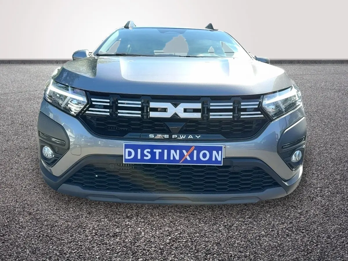 Vue frontale d'une Dacia Sandero Stepway gris foncé avec calandre noire et feux LED allumés.