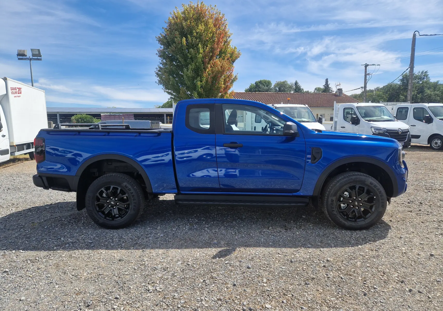 Ford Ranger Super Cabine bleu Lightning vu de profil côté gauche, avec plateau protégé par un rideau rigide coulissant.