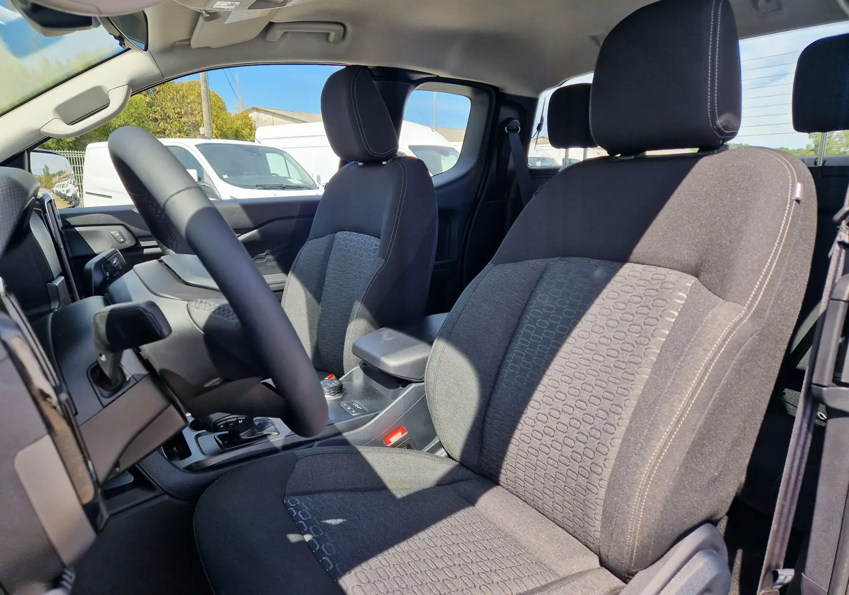 Vue intérieure côté conducteur du Ford Ranger Super Cabine bleu Lightning, mettant en valeur les sièges avant en tissu gris.