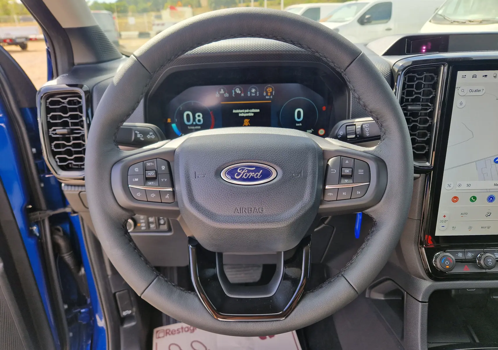 Vue intérieure centrée sur le volant du Ford Ranger Super Cabine bleu Lightning avec tableau de bord numérique et écran tactile.
