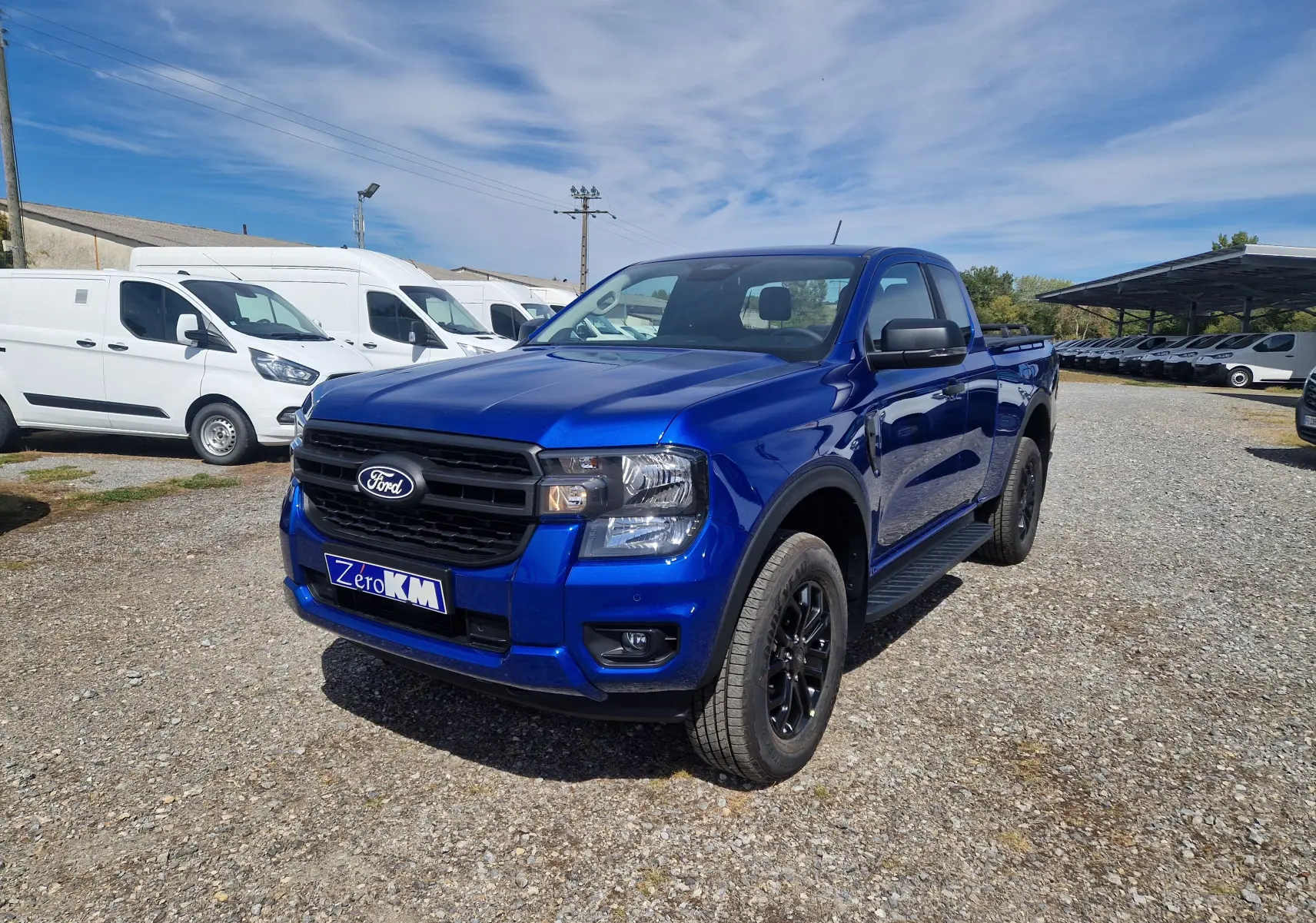 Ford Ranger Super Cabine bleu Lightning en 3/4 avant droit, avec jantes noires et marchepied visible.