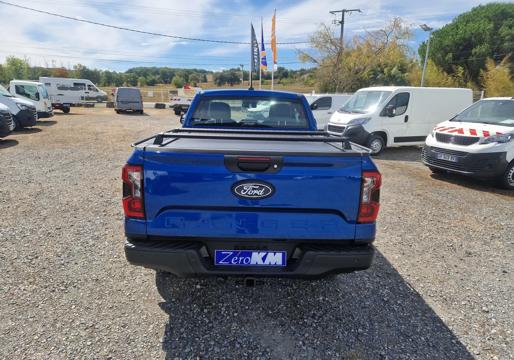 Vue arrière d'un Ford Ranger Super Cabine bleu Lightning avec rideau de plateau rigide et attelage visible.