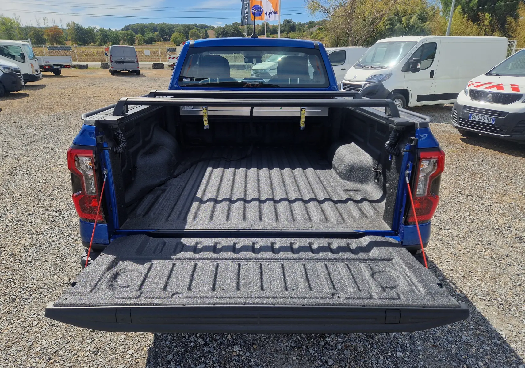 Vue arrière du Ford Ranger Super Cabine bleu Lightning avec plateau ouvert et rideau rigide coulissant visible.