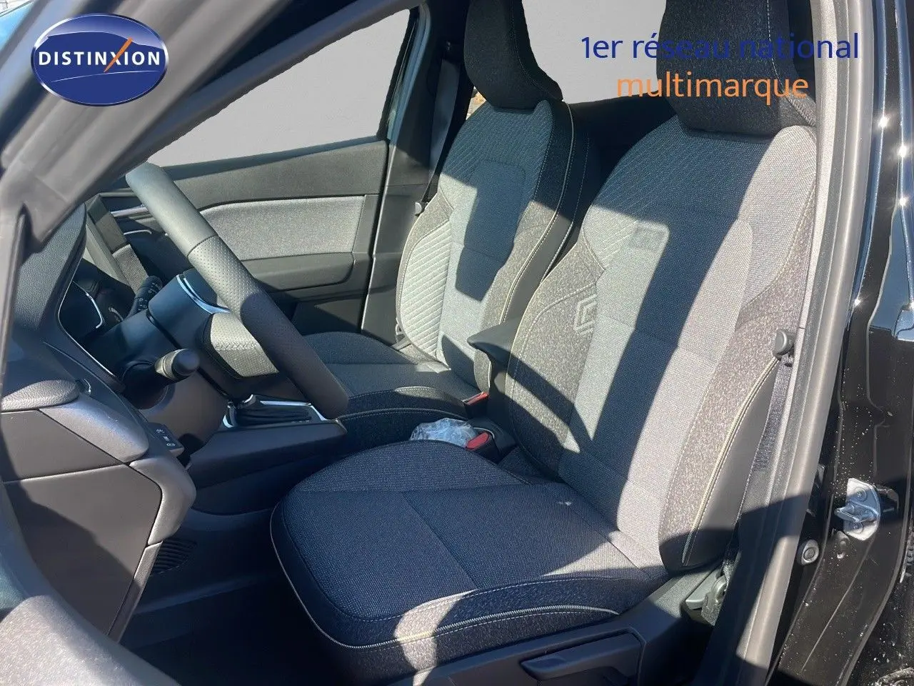 Intérieur avant droit du Renault Captur E-Tech hybride 2025 avec sièges tissu gris et volant noir visible.