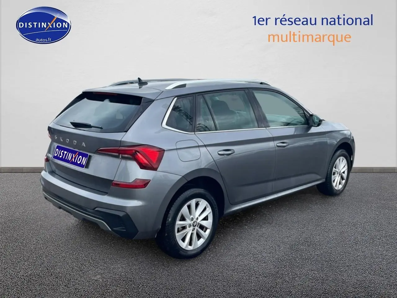 Vue 3/4 arrière droite d'un Skoda Kamiq gris 2025 avec barres de toit et jantes alu.