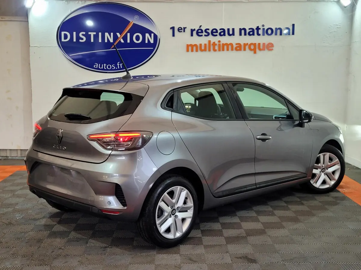 Renault Clio Evolution Blue dCi 100 gris foncé vue 3/4 arrière droit avec feux LED allumés en intérieur showroom.