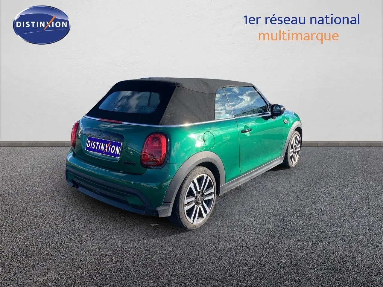 Vue 3/4 arrière droite d'une MINI Cabriolet F57 2023 British Racing Green avec toit souple noir fermé.