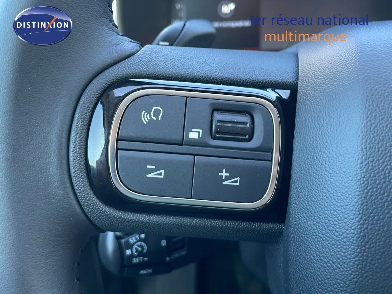 Gros plan sur les commandes du volant à gauche du Citroën C5 Aircross gris platinium 2025 avec toit noir.