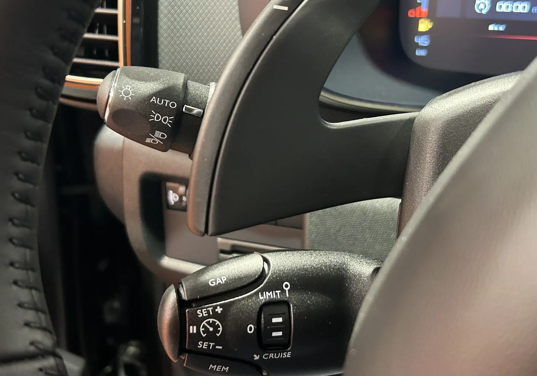 Gros plan sur les commandes au volant noir du Citroën C5 Aircross 2025, avec réglages des phares et régulateur de vitesse.
