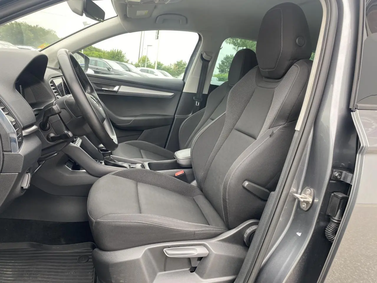 Intérieur côté conducteur du Skoda Karoq gris graphite, sièges tissu noir et tableau de bord visible en arrière-plan.