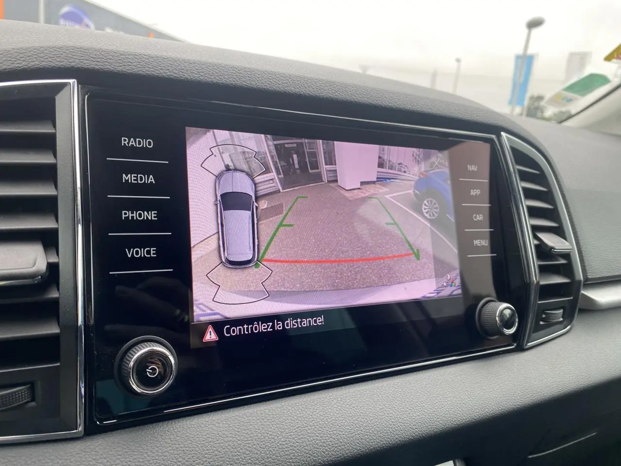 Écran tactile intérieur montrant la caméra de recul du Skoda Karoq gris graphite, avec lignes de guidage colorées.