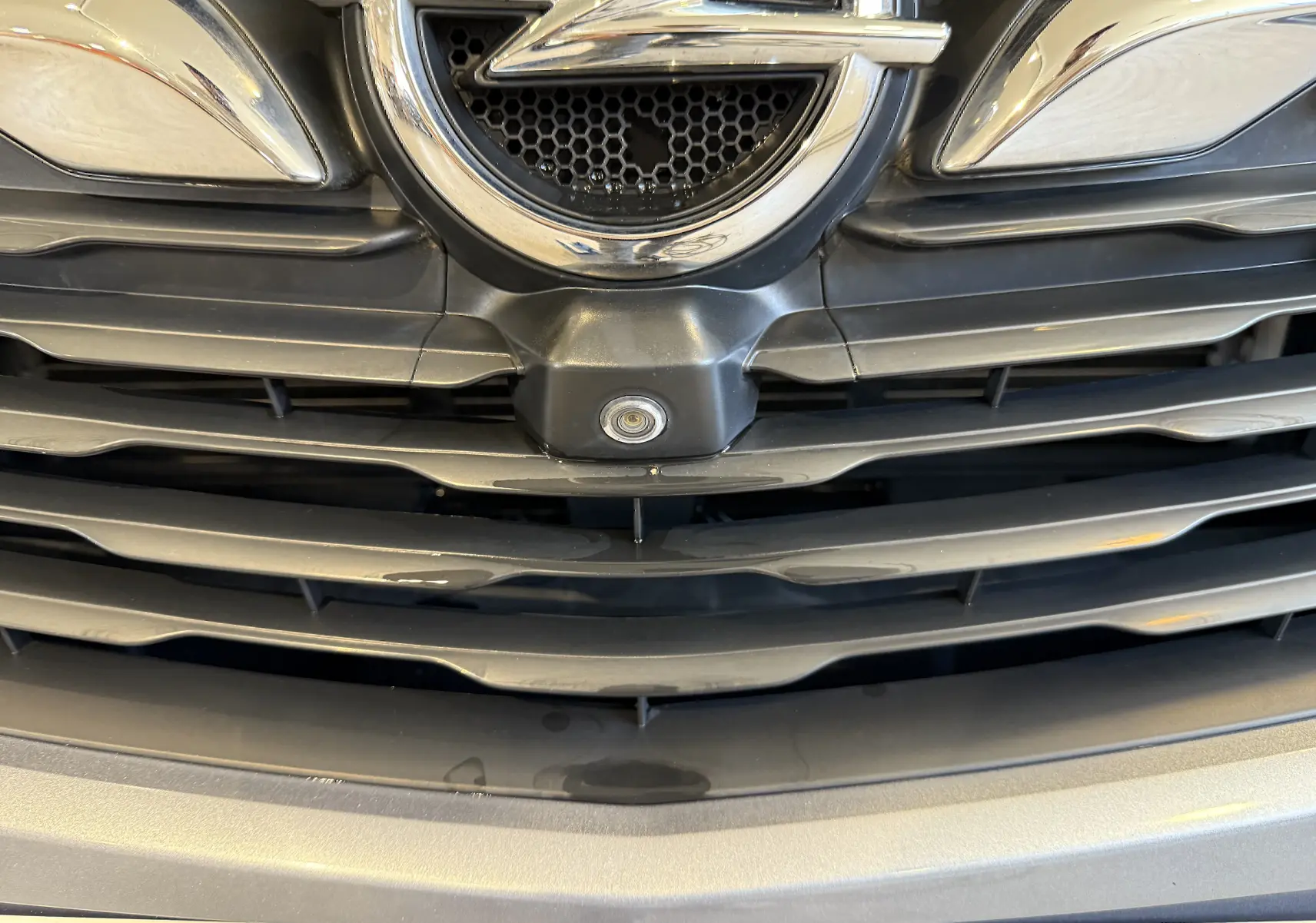 Gros plan sur la calandre gris métallisé de l’Opel Grandland X 1.6 Hybrid Turbo 2021 avec caméra frontale intégrée.